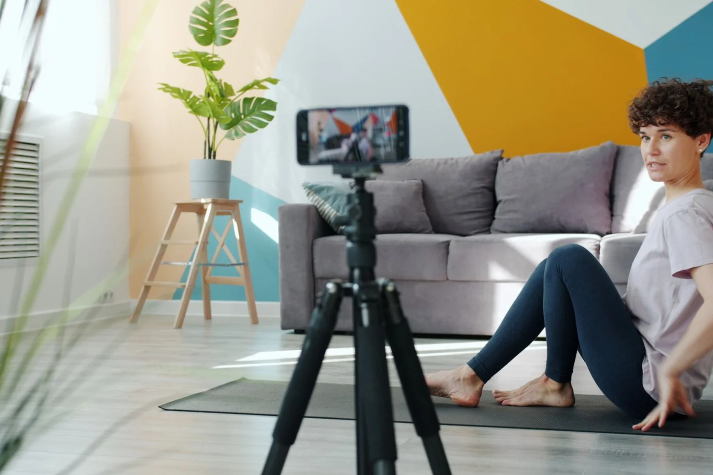 A phone on a tripod recording a home exercise space.
