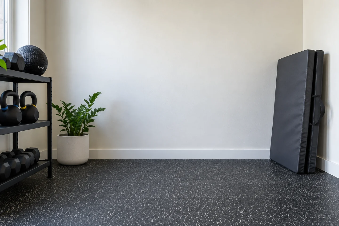 Uncluttered interior wall and nonslip floor beside a folded mat.