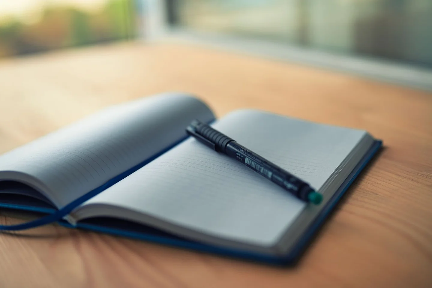 A pen resting across an open notebook.
