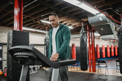A person checking a treadmill console before using it.